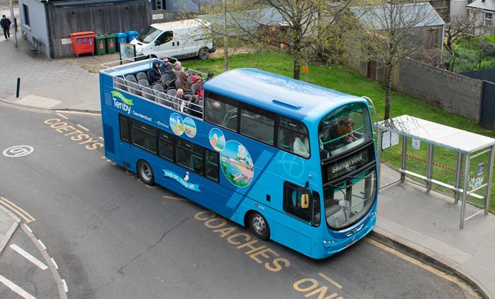 an open-top bus parked in a bus stop